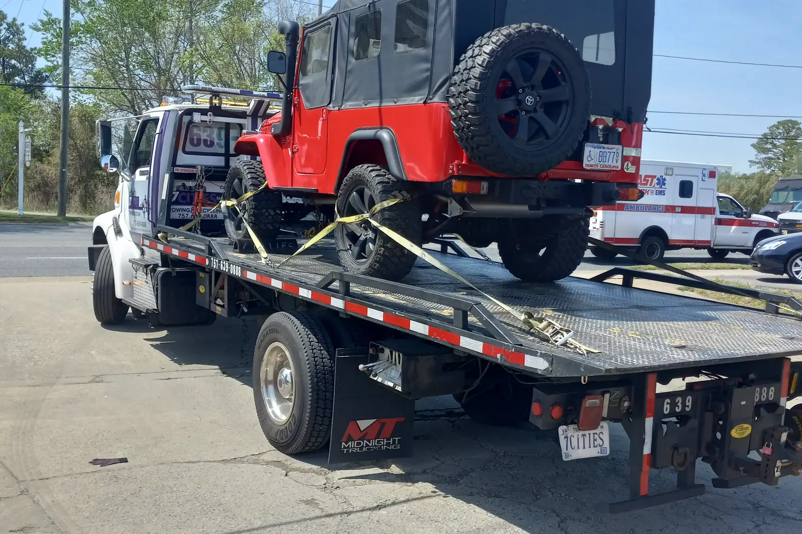 A red Jeep Wrangler strapped down on a 7 Cities flatbed